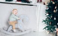 Small boy riding a horse in white room decorating for Christmas and winter holidays. Playing alone and having fun. Part Royalty Free Stock Photo