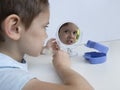 Small boy with round mirror,which reflects his face,inserts orthodontic silicone device to correct bite into his mouth