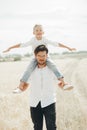 Small boy is sitting on his father shoulders a in the wheat field