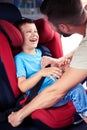 Small boy smiling while his father helps to fasten belt on car s Royalty Free Stock Photo