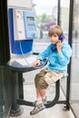 Small boy speaks by public pay telephone Royalty Free Stock Photo