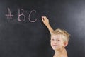 A small boy without a T-shirt writes ABC on the blackboard Royalty Free Stock Photo