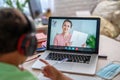 Small boy uses laptop to make video call with his teacher. over his shoulder