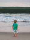 Small boy watching big wave approach
