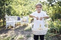 Small boy in a white t-shirt is holding a pottle with cute pet nestlings. Child and birds