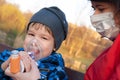 A small boy who suffering from illness bronchial asthma getting treatment with aerosol inhaler outdoors Royalty Free Stock Photo