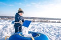 A small boy of 4-5 years old, playing in snow with a spatula, in winter outside. The guy throws snow in tubing. Royalty Free Stock Photo
