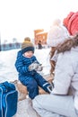 A small boy of 4-6 years old, sitting on a bench, in the winter in the city on the rink. Waiting for Mom to put on Royalty Free Stock Photo