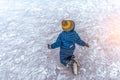 Small boy of 2-3 years old, wearing skirt, fell on ice his skates. Concept first lesson of skating support , failure and Royalty Free Stock Photo