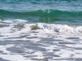 Small breaking waves with foam on the beach of the Black Sea