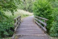 Small bridge over a stream with a pedestrian path leading into nature reserve Royalty Free Stock Photo