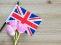 Small British flag with pink tulips on a wood background Royalty Free Stock Photo