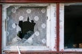 Small broken window with red frame and window shades torn apart. Detail of an old abandoned house, falling apart