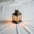 A small bronze colored lantern rests on a white fabric surface Royalty Free Stock Photo