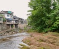 Small brook before aged dwelling buildings in light summer rain