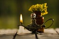 Small brown medicine bottle for magicians remedy, Aladin type lamp and white wax candle sitting on wooden surface