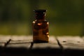 Small brown medicine bottle for magicians remedy sitting on wooden surface, beautiful night light setting, magic concept