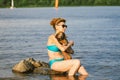 A small brown, old dog of a Dachshund breed sits on the hands of a mature woman in a pond. Theme to spend the summer swimming in