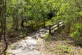 A small brown wooden bridge over a lake on a dirt footpath in the forest surrounded by lush green trees at Callaway Gardens Royalty Free Stock Photo