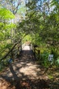 A small brown wooden bridge over a silky green lake surrounded by lush green trees and plants at Callaway Gardens Royalty Free Stock Photo