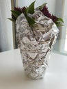 A small bunch of basil in a cup wrapped with tin foil