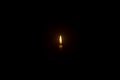 Small burning candle flame or light glowing on a white candle on black or dark background on table in church for Christmas, Royalty Free Stock Photo