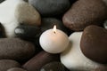 Small burning candle on spa stones