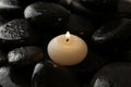 Small burning candle on wet spa stones