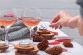 Small burning candles, two glasses with rose wine, cones, dry red leaves, gray scarf knitted on a white wooden table. Royalty Free Stock Photo