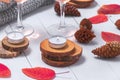 Small burning candles, two glasses with rose wine, cones, dry red leaves, a gray scarf knitted on a white wooden table. Royalty Free Stock Photo