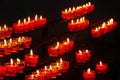 small burning church candles in red glass candleholders photographed diagonally on the chandelier Royalty Free Stock Photo