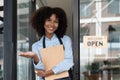 Small business african female owner smiling while turning sign for opening of cafe. Happy afro-american waitress Royalty Free Stock Photo