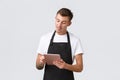 Small business, coffee shop and cafe employees concept. Handsome young guy barista, waiter taking order, serving tables Royalty Free Stock Photo