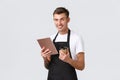 Small business, coffee shop, cafe and restaurants concept. Handsome smiling barista, waiter in black apron serving Royalty Free Stock Photo