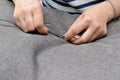Small business concept. Woman sews button on a gray fabric, horizontal photo