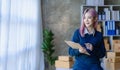 Small Business Entrepreneur SME owner cute young asian woman checking orders with laptop computer using smartphone checking orders Royalty Free Stock Photo