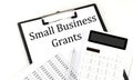SMALL BUSINESS GRANTS text on folder with chart and calculator on white background Royalty Free Stock Photo