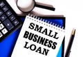 SMALL BUSINESS LOAN written in a white notepad near a magnifier, calculator and pen. Credit concept Royalty Free Stock Photo