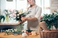 Smiling lovely young woman florist arranging plants in flower shop Royalty Free Stock Photo