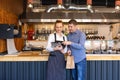 Small business owner couple in little family restaurant looking at tablet for online orders