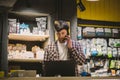 Small business owner on phone and computer in store. Sport shop worker making call with cell phone. Salesman working and talking Royalty Free Stock Photo