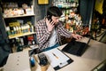 Small business owner on phone and computer in store. Sport shop worker making call with cell phone. Salesman working and talking Royalty Free Stock Photo