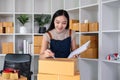 A small business owner receives product orders and writes shipping information on cardboard boxes in the home office to Royalty Free Stock Photo