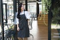 small business owner standing at coffee shop. female barista wearing apron smiling at cafe. food service, restaurant concept. Royalty Free Stock Photo