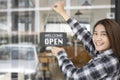 Small business owner turning open sign board on glass window. Royalty Free Stock Photo