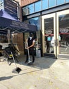 Small business owner wearing mask and sweeping the fall leaves