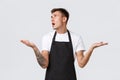 Small business owners, coffee shop and staff concept. Confused and annoyed guy barista, waiter in black apron, roll eyes Royalty Free Stock Photo