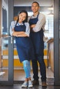 Small business owners standing at the entrance of their coffee shop, proud and ready for customer. Young power couple