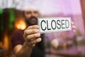 Owner puts closed sign at bar or restaurant window