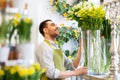 Happy florist man setting flowers at flower shop